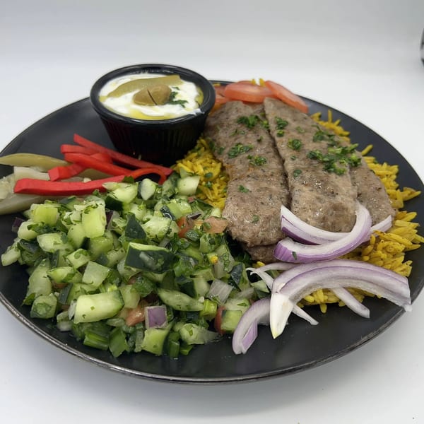 Falafel Hut's Mediterranean plate with kebab, yellow rice, cucumber salad, red onions, and dipping sauce.