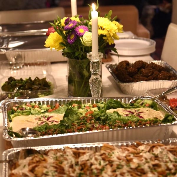 A buffet of Mediterranean dishes, including falafel, salads, and shawarma, with a floral centerpiece.
