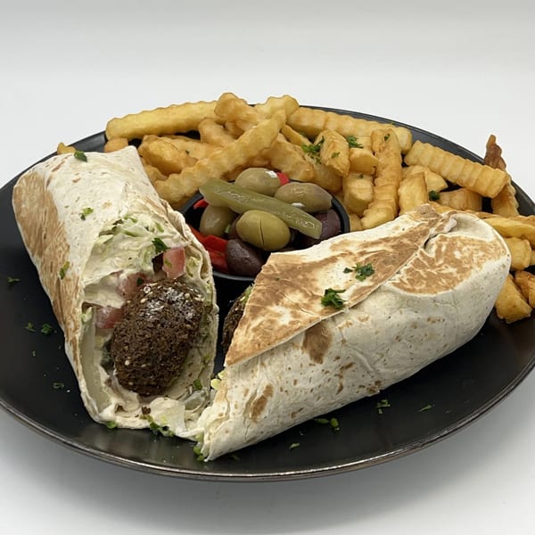 Falafel Hut's falafel wraps, crinkle-cut fries, and a side of olives and pickles on a black plate.