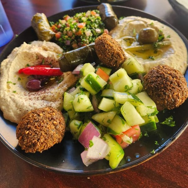 A Falafel Hut platter with hummus, falafel, cucumber salad, tabbouleh, and stuffed grape leaves.